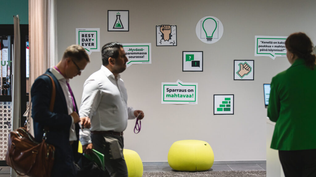 Kasvu Open -sparraustilaisuudessa ihmisiä kävelemässä julisteseinän ohitse