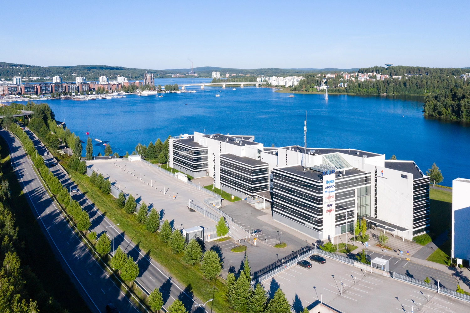 Toimitilakiinteistö Jyväskylän Mattilanniemi 6-8, ilmakuvattuna Rantaväylän päältä. 3 toisiinsa yhteen rakennettua toimistotaloa Jyväsjärven rannassa. Edustalla pysäköintitalo.