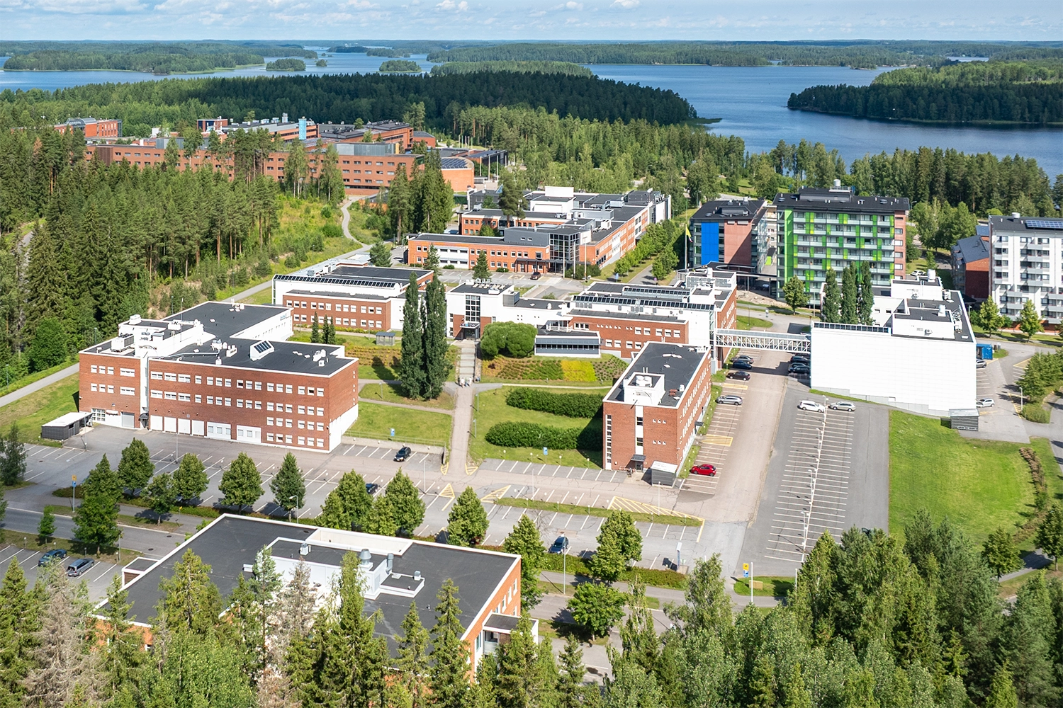 Kielo Lappeenranta – Laserkatu 6 useita toimitilarakennuksia, joissa tiilijulkisivu. Rakennusten edessä parkkipaikkoja, takana järvi ja metsää.