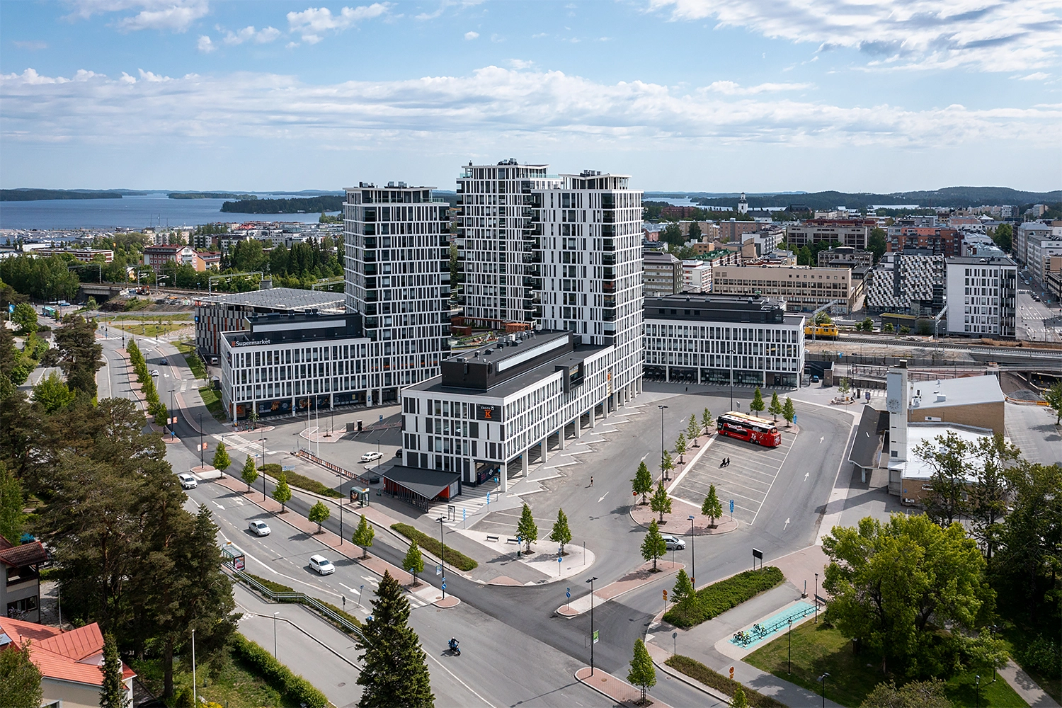 Ilmakuva Kuopion Portti -rakennuskokonaisuudesta. Valkoisissa rakennuksissa on korkeat asuintornit. Edessä linja-autoasema, takana juna-asema.