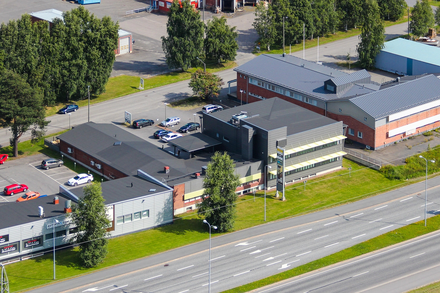 Oulun Voudintie 4, ilmakuva. Kiinteistö koostuu punatiilisestä, matalasta rakennuksesta sekä kaksikerroksisesta, harmaasta osasta. Kiinteistön edessä on monikaistainen tie, talon takana pysäköintialue