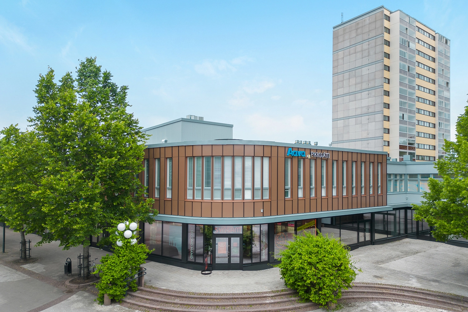 Kauppakaari 15 on 2-kerroksinen ruskea kulmasta kaareva liikerakennus kävelykadun varrella Keravalla. Talon sivustoilla kasvaa lehtipuita.