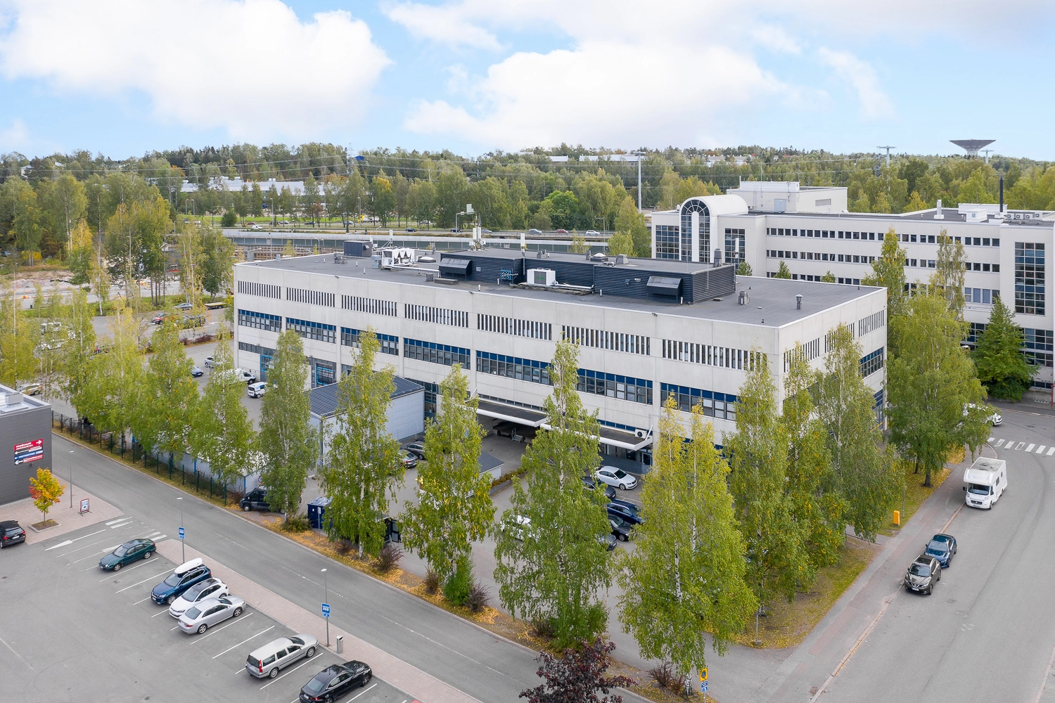 Helsingin Laippatie 1, ilmakuva. Vaalea, laatikkomainen rakennus jossa monta kerrosta. Rakennuksen ympärillä puita, sekä asfaltoitu piha jossa autoja pysäköitynä. 